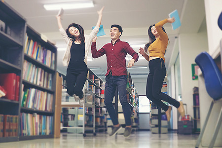 一群学生在图书馆里跳跃 似乎很高兴学校团体青少年乐趣图书友谊背景图片