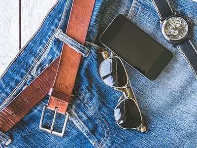 雄性饰物 衣服和工具的顶端景色手表眼镜配饰男性太阳镜电话裤子手机男人皮革背景图片