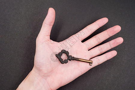 男性手持黑色背景的金属钥匙图片