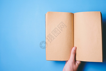 手持空白书的顶端视图 该书备有复制空间 可以用于蓝背景文字图片