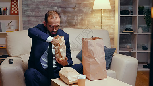 追赶饥饿的天主教商务人士西装照的照片男人正装程序垃圾食物客厅薯条交换电视遥控图片