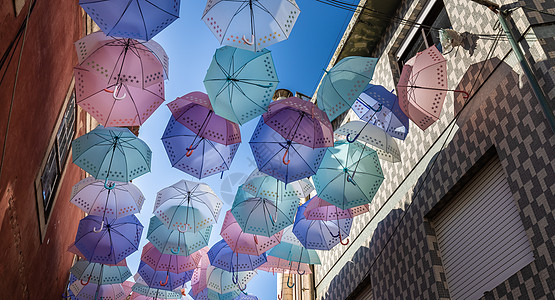 街头雨伞高高挂起来 以防波图格的雨水和太阳照射天空彩色元素阳光村庄蓝色背景橙子遮阳棚文化图片