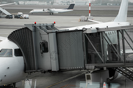 机场上的飞机连接到门套 飞机和套筒 机场门口供乘客登机假期跑道旅行燃料方法服务建筑袖子商业天空背景图片