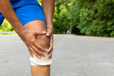 穿蓝短裤的人跑后用手抓膝盖髌骨身体成人伤害运动员男人训练痛苦跑步扭伤图片
