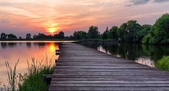 日落时穿过湖边的木道长廊公园旅行人行道闲暇溪流水景途径池塘旅游图片