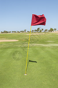 绿色高尔夫球场的旗帜旗杆休闲运动蓝色红色娱乐天空阴影黄色热带图片