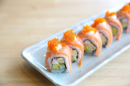 以木本为背景的鲑鱼寿司卷饮食红色盘子食物寿司黑色美食海鲜餐厅蔬菜图片