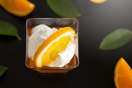 杯子中的橘子果冻加奶油和橙汁美食叶子食物绿色明胶橙子果味水果白色小吃图片