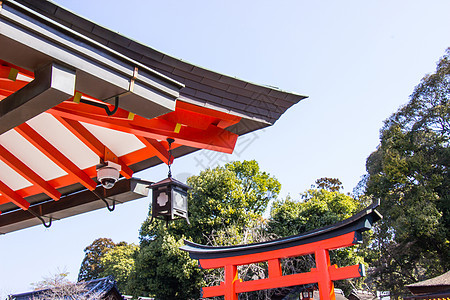 伏见 Inari 神社内的安全系统闭路电视和日本传统木制寺庙屋顶的细节是日本京都著名的神社旅游橙子旅行天空佛教徒文化精神途径地标图片