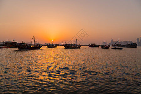 传统三角帆船起重机反射日落海湾景观首都建筑物独桅商业城市图片