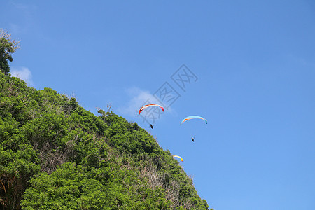 在天空中滑翔伞 三架单人滑翔伞在夏日飞越热带巴厘岛 美丽的滑翔伞在绿松石色的背景下飞行 积极的生活方式和极限运动的概念自由蓝色肾图片