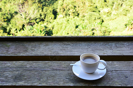 绿色背景的木制桌边咖啡杯图片