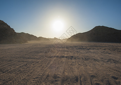 穿越干旱沙漠的车辆跟踪地平线勘探砂岩岩石太阳冒险日落旅行环境气候图片