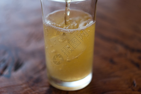 把啤酒水倒在玻璃上 冰和霜金子桌子酒精酿造气泡饮料庆典瓶子生活木头图片