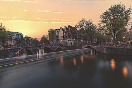 在荷兰蓝色日落时间在阿姆斯特丹平静运河上航行的长度暴露船首都运输房子景观照明建筑学街道反射历史性场景图片