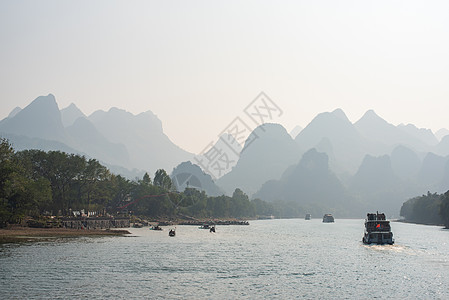 李河巡航和喀斯特在吉林形成山地风景的轮船石灰石旅游场景顶峰蓝色山脉爬坡晴天薄雾农村图片