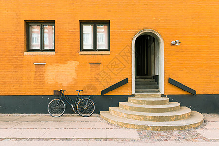 在丹麦哥本哈根老住宅大楼的橘黄色墙附近 旧居民Bui Black自行车在墙附近停靠图片