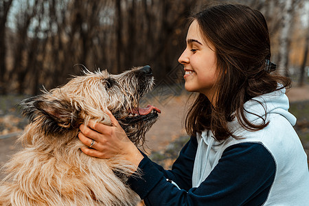 动物训练 一名志愿者女孩从动物收容所带着一只狗散步 在秋天的公园里带着狗的女孩 和狗一起散步 照顾动物幸福运动跑步闲暇朋友女士友图片
