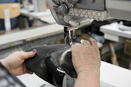 皮革车间的缝纫机在用手处理鞋子的皮革细节 在鞋厂 老妇人的手拿着缝纫机制造业行动工人工作裁缝工艺压缩水牛机器衣服图片