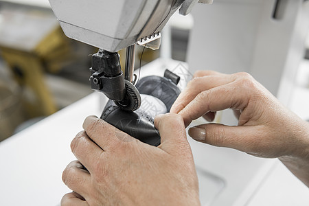 皮革车间的缝纫机在用手处理鞋子的皮革细节 在鞋厂 老妇人的手拿着缝纫机裁缝作坊压缩商业生产工人制造业机械工厂工艺图片