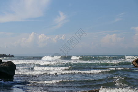 印度尼西亚巴厘岛退潮时海浪冲上岸 水在石头上层叠 滋养潮汐池 在海神庙附近的退潮期间 波浪在岩石上破碎 深蓝色的海洋和天空在背景背景图片