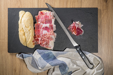 用刀子 番茄和大蒜 配有伊比里亚橡皮火腿三明治 西班牙典型的塔帕斯红色早餐小吃美食面包火腿木头餐厅猪肉食物图片
