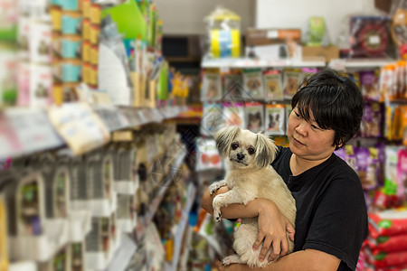 妇女及其宠物店的狗店货架公司走道动物店铺商品食物消费者购物中心商业图片