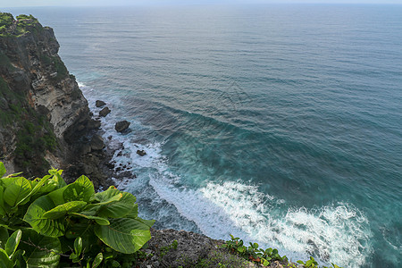 印度尼西亚巴厘岛的乌鲁瓦图悬崖与凉亭和蓝色大海的景色 寺的美丽风景 白天有五颜六色的鲜花前景 高悬崖风景秀丽的沿海景观地标海洋岩图片