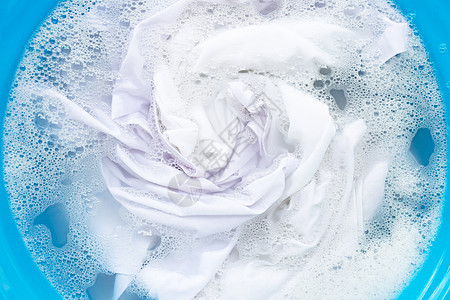 白色衣服浸泡在粉末洗涤水溶解中图片