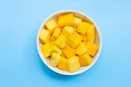 热带水果 芒果立方块 在蓝色的草原上的白碗中切片叶子蔬菜甜点植物维生素食物饮食营养沙拉小吃图片