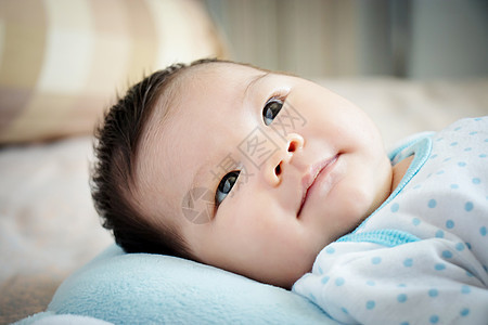 亚洲婴儿肖像 白天 可爱的亚洲女婴在舒适的床上睁开眼睛 微笑着寻找父母 快乐的儿童概念图片