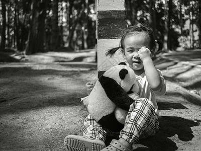 亚洲小孩独自坐在松树林的路上哭泣和抱抱熊时 坐着图片