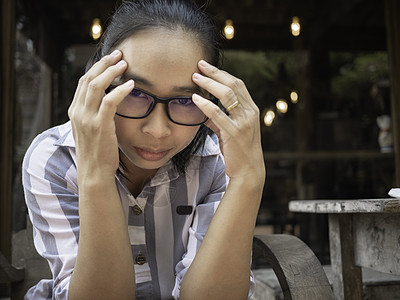 戴眼镜的女人戴眼镜的亚洲青年妇女头痛 手放在头上 表情和健康上浮肿偏头痛女性压力悲伤眼睛成人焦虑女士工人眼镜背景