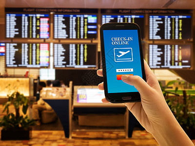 旅行者智能手机应用程序概念 国际机场女性手的特写使用手机在线办理登机手续 并带有航班信息板背景 检查她的航班 无名脸图片