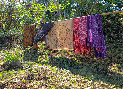 Sarong 或 Sarung 是巴厘岛印度教徒在仪式期间穿的传统服装 披在竹干上的彩色织物在阳光下晒干 悬浮洗涤物图片