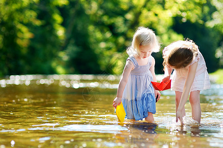 两个小妹妹玩纸船的两姐妹自由家庭孩子们团队童年姐姐朋友们女性森林池塘图片