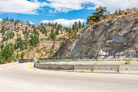 不列颠哥伦比亚Okanagan山谷的山路近弯障碍汽车晴天罐头树木速度蓝色石头岩石驾驶图片