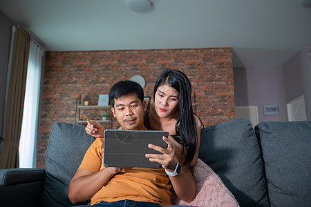 网上买亚洲情侣 用笔记本电脑用信用卡付账 在家在沙发上冲网的幸福夫妇房间丈夫微笑信用银行业互联网男性女士支付购物图片