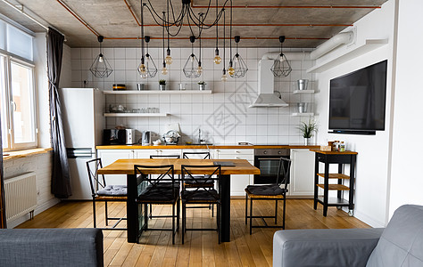 现代斯堪的纳维亚式厨房室内设计 大木桌和椅子与浅色木地板 明亮的白色墙壁和带电视 电器和悬挂灯泡的家具橡木桌子架子奢华日光农家餐图片