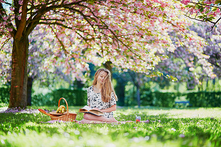 在盛开的春天公园 美丽的年轻女子阅读成人过敏农村花园水果面包花瓣花粉小吃图片