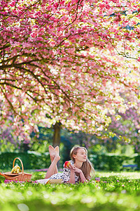 在盛开的春天公园野餐的年轻美女糖果水果面包农村小吃成人阳光季节过敏闲暇图片