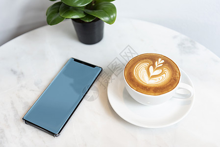 卡布奇诺咖啡在咖啡店的大理石桌子上 手机空白屏 模拟广告饮料咖啡商业杯子牛奶手机屏幕小样互联网店铺图片