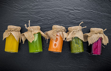 黑石上瓶子里有丰富多彩 健康的冰雪和果汁饮料石榴彩虹茶点蔬菜饮食浆果活力黄瓜纤维图片