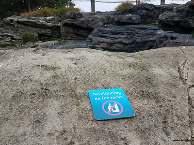 蓝不攀升在岩石标志上安全指示牌石头巨石背景图片