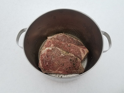 牛肉牛排 配有调料和雪上金属锅中的液体午餐牛扒冷冻白色食物图片