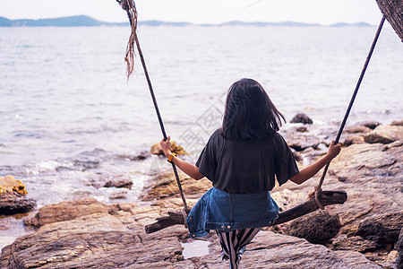 女人和夏日海滩一起坐在秋千上图片