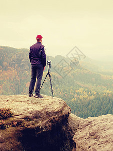 高大成人摄影师准备拍摄秋山的相机 笑声背包国家空间男人远足者孤独日落摄影远景冒险图片