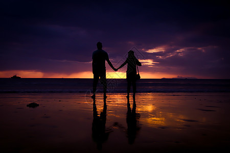 一对夫妇的休丽花 牵起彼此的手 欢乐的年轻情侣 在日落时在沙滩上相爱夫妻家庭阳光女性情人男人海洋海岸男性蜜月图片