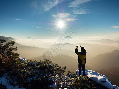 希克人头顶举起电话 拍摄迷雾的冬季风景图片