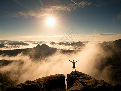喜悦的人类胜利的姿态 在岩石峰顶上用公羊在空中飞翔游客裤子薄雾顶峰衬衫手势男生旅行阴影空气图片